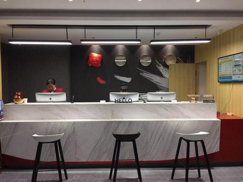 a counter with two stools and a man sitting at a bar at Thank Inn Plus Hotel Shandong Zibo Zhangdian District Jinjing Avenue Wanxianghui in Zibo