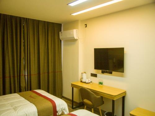 um quarto de hotel com uma secretária e uma cama em Thank Inn Plus Hotel Jiangxi Nanchang Gaoxin Development Zone 2nd Huoju Road em Nanchang
