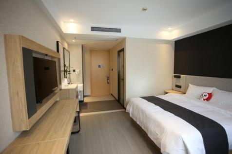 a bedroom with a large bed and a flat screen tv at Thank Inn Plus Jiangsu Zhenjiang Jiangkou District Hongdou Square in Zhenjiang