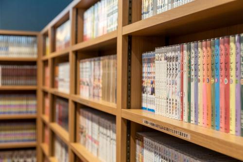 a row of books on shelves in a library at Dormy Inn Kawasaki Natural Hot Spring in Kawasaki