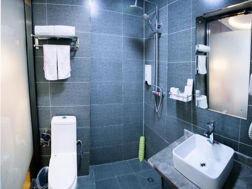 ein Badezimmer mit einem Waschbecken, einem WC und einem Spiegel in der Unterkunft Thank Inn Plus Hotel Gansu Pingliang Kongtong District Fengshou Road in Pingliang
