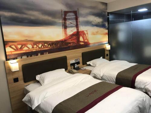 two beds in a hotel room with a painting on the wall at Thank Inn Plus Hotel Anhui Huibei Xiangshan District Suixi Middle Road in Huaibei