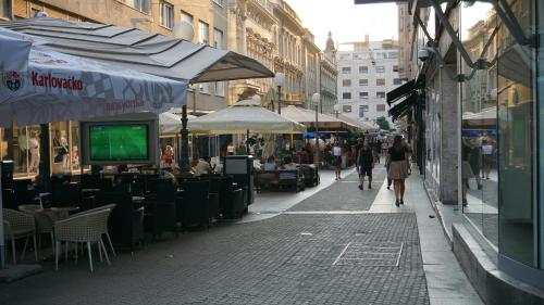 a street with tables and chairs and people walking down the street at Karlo Main Square Apartments in Zagreb