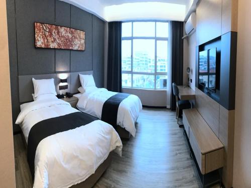 a hotel room with two beds and a television at Up And In Guangdong Zhongshan West District Caihong Street in Zhongshan