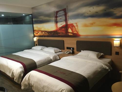 two beds in a hotel room with a painting on the wall at Thank Inn Plus Hotel Henan Sanmenxia Lingbao Changan Road in Sanmenxia