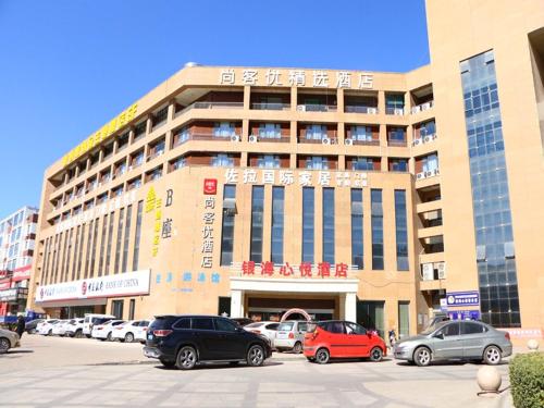 a large building with cars parked in a parking lot at Thank Inn Plus Hotel Shanxi Jinzhong Yuci District Yingbin West Street Yinhaixinyue in Jinzhong