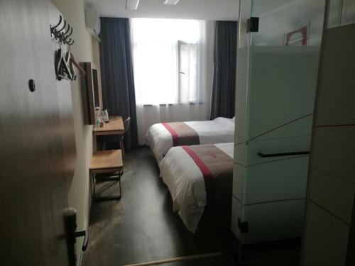 Habitación de hotel con 2 camas, escritorio y ventana en Thank Inn Plus Hotel Shandong Taian Xintai City Qinglong Road, en Zhaizhen