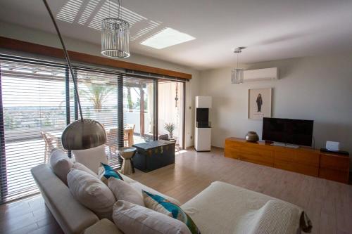 a living room with a couch and a television at Penthouse Duplex overlooking the Mediterranean in Larnaka