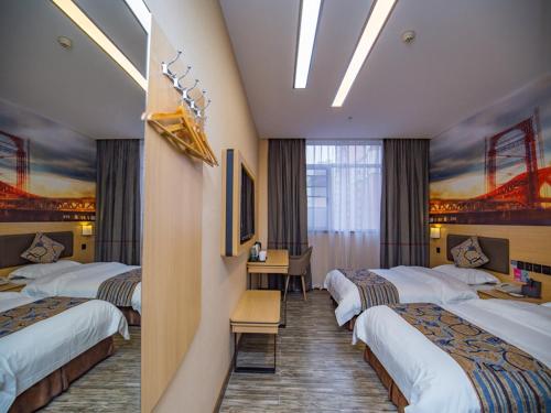a hotel room with four beds and a desk at Thank Inn Plus Hotel Hubei Jingzhou City Jingzhou District Railway Station in Jingzhou