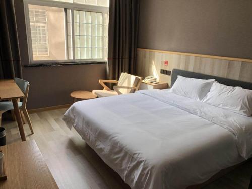 1 dormitorio con cama blanca, sillas y ventana en Up And In HuBei Jingzhou Jiangling xian Jiangling Road, en Jingzhou