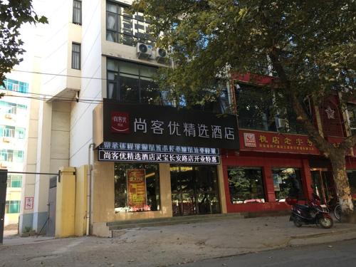un bâtiment avec un panneau sur le côté d'une rue dans l'établissement Thank Inn Plus Hotel Henan Sanmenxia Lingbao Changan Road, à Sanmenxia