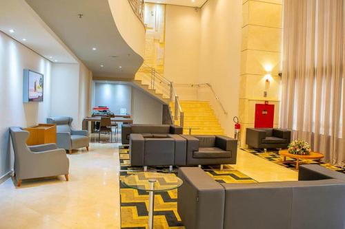 a lobby with couches and chairs and a staircase at Airport Business Flat Guarulhos - São Paulo in Guarulhos