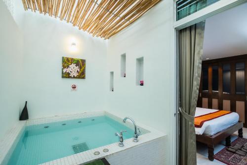 ein Bad mit einer Badewanne und einem Bett im Hintergrund in der Unterkunft Kata Tranquil Villa - SHA Plus in Karon Beach