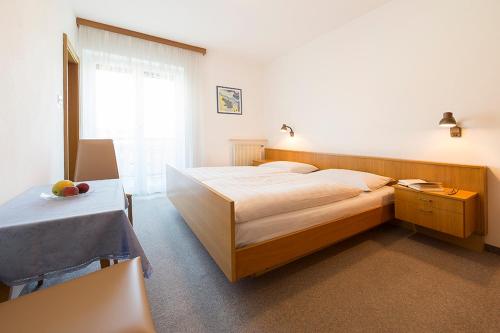 Un dormitorio con una cama grande y una ventana en Pension Etschland, en Tirolo