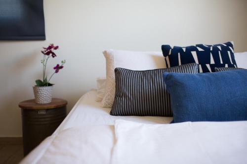 a white bed with blue pillows and a plant on a table at Penthouse Duplex overlooking the Mediterranean in Larnaka