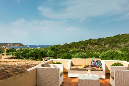 a patio with white furniture and a view of the ocean at CPH | Pevero Hotel in Porto Cervo