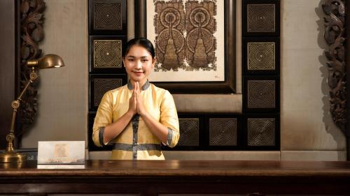 a woman is sitting at a table with her hands in front at Mane Boutique Hotel & Spa in Siem Reap