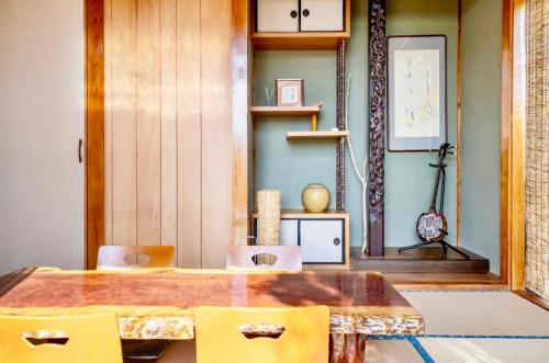 jadalnia z drewnianym stołem i żółtymi krzesłami w obiekcie 沖縄の自然と文化を体験できるゲストハウス一番座 w mieście Nanjo
