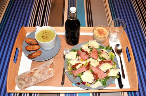 ein Tablett mit einem Teller Essen, einem Teller Brot und einem Teller in der Unterkunft Maison d'hôtes MIRADOUR in Tarnos