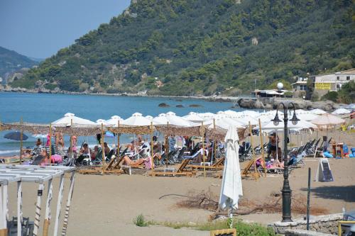 a beach with umbrellas and people on the beach at Sofia Margarita's Rooms in Agios Gordios
