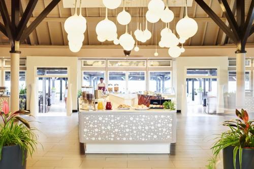 a restaurant with a counter with a person preparing food at LUX* Saint Gilles Resort in Saint-Gilles les Bains