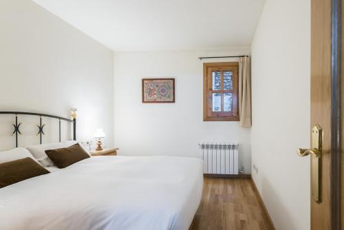 a white bedroom with a white bed and a window at Apartamento Refugi in Canillo