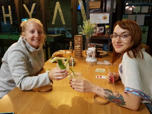 two women sitting at a table with drinks at Wayha Hostel Don Mueang Airport in Bangkok