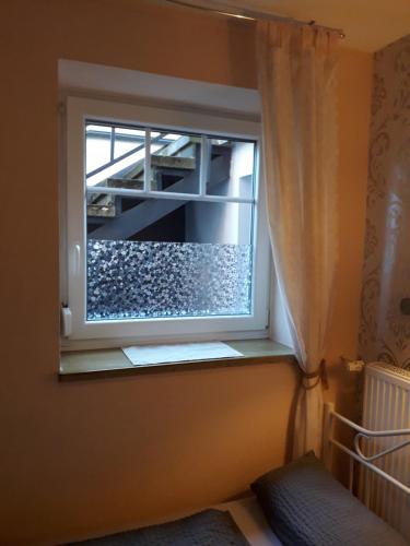 a window with a curtain in a bedroom at Gästehaus Strandkonsulat in Scharbeutz