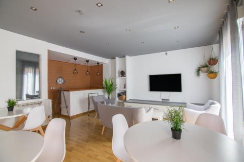 a living room with white tables and chairs and a television at Tinto Dreams Hostel in Haro