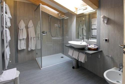 bagno con doccia, lavandino e servizi igienici di Hotel Flora Alpina a Campitello di Fassa