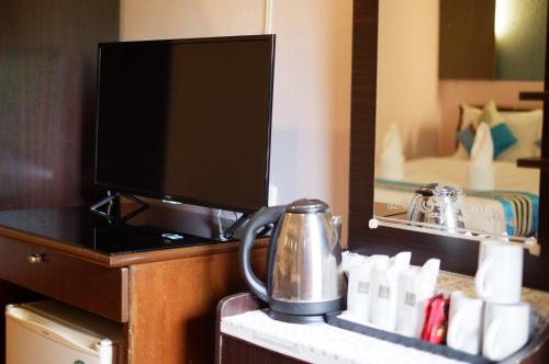 Cette chambre d'hôtel dispose d'une bouilloire sur une table. dans l'établissement Khaolak Grand City, à Khao Lak