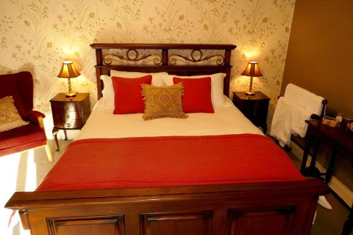 a bedroom with a large bed with red pillows at Crookedstone House in Antrim