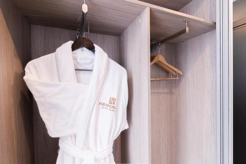 a white robe is hanging in a room at Resident City Hotel in Almaty
