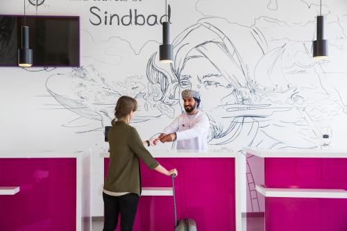 a man and a woman standing at a counter in a room at Mercure Sohar in Sohar