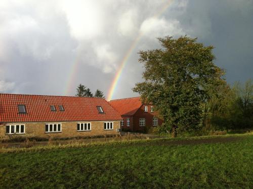 a rainbow in the sky over two houses at Agerdal - dejligt hus midt i mark og have in Nykøbing Mors