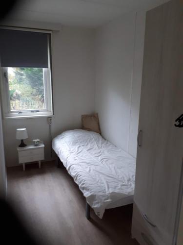 a small bedroom with a bed and a window at Boshut Schoorl in Schoorl