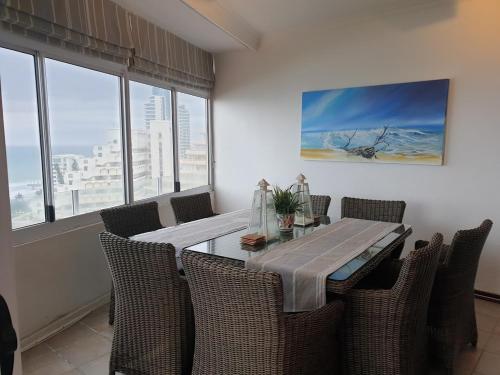 a dining room with a table and chairs and windows at 105 Sea Lodge in Durban