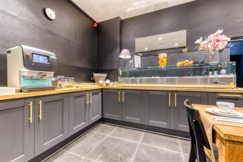 une cuisine avec des placards gris et un comptoir dans l'établissement Hôtel de la Gare, à Visé