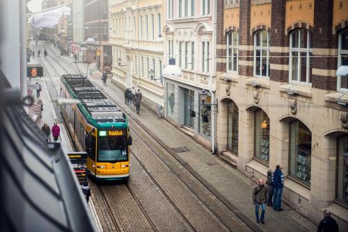 a yellow and green train on tracks in a city at The Lamp Hotel & Spa in Norrköping