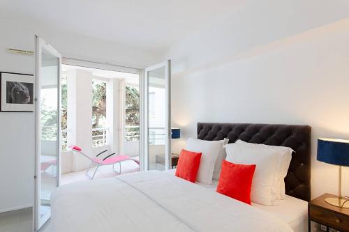 une chambre avec un grand lit blanc avec des oreillers rouges dans l'établissement MARTINEZ HOTEL AREA: Modern 3 bedrooms w/ terrace, à Cannes