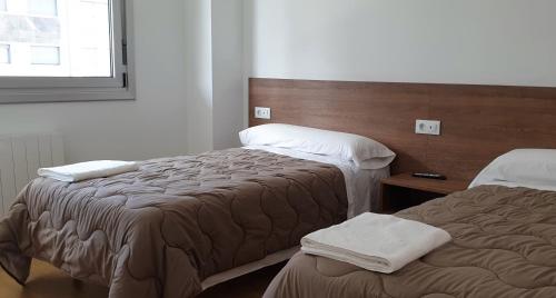 a hotel room with two beds and a window at Pension Cando in Porriño