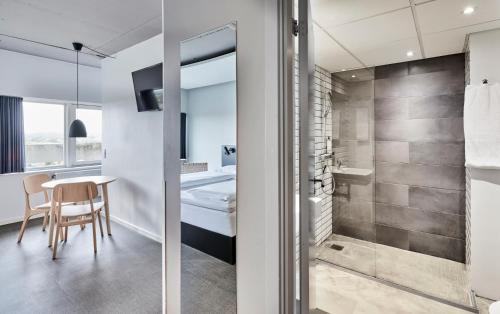 a bathroom with a shower and a table with a chair at Zleep Hotel Aarhus Viby in Aarhus