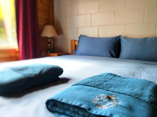 a bed with two blue pillows on it at Twelve Apostles Motel & Country Retreat in Princetown