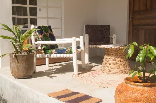 a porch with two chairs and potted plants at Villa Kiota in Paje
