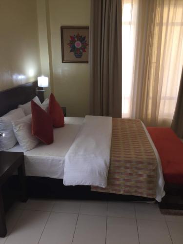 a bedroom with a large bed with red pillows at AMOR Hotels Ekiti in Ado Ekiti