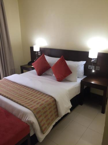 a bed with two red pillows on top of it at AMOR Hotels Ekiti in Ado Ekiti