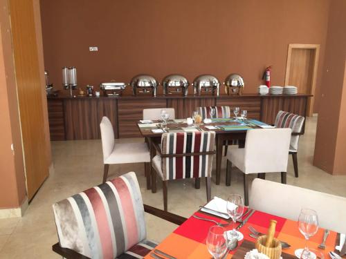 a dining room with a table and white chairs at AMOR Hotels Ekiti in Ado Ekiti