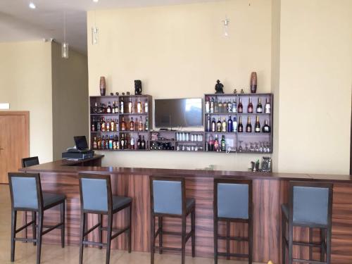 a bar with four chairs and a counter with alcohol at AMOR Hotels Ekiti in Ado Ekiti