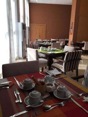 a dining room with tables and chairs with silverware at AMOR Hotels Ekiti in Ado Ekiti