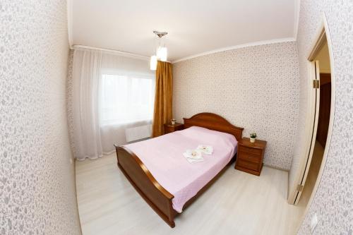 a small bedroom with a pink bed and a window at Двухкомнатные просторные апартаменты RentHome в ЖК Кемерово-Сити in Kemerovo